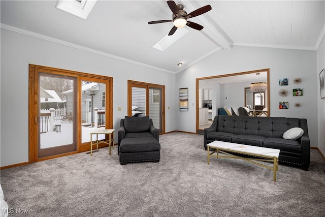 carpeted living room with ceiling fan, lofted ceiling with skylight, and ornamental molding