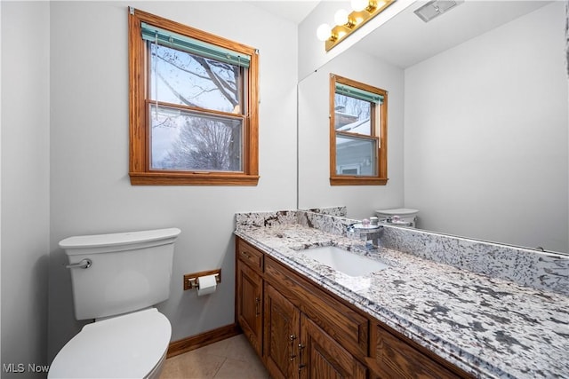 bathroom with toilet, vanity, and tile patterned floors