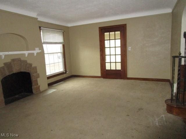 unfurnished living room featuring a wealth of natural light, a fireplace, and light carpet