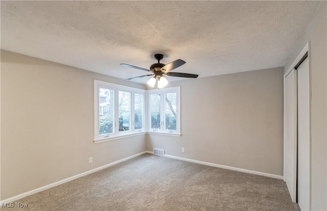 unfurnished bedroom with carpet, ceiling fan, a textured ceiling, and a closet