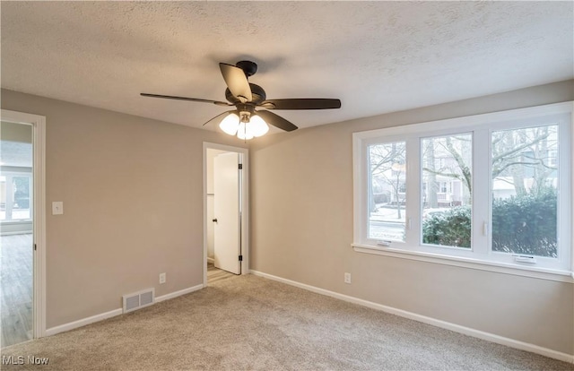 unfurnished room featuring a textured ceiling, light colored carpet, and ceiling fan