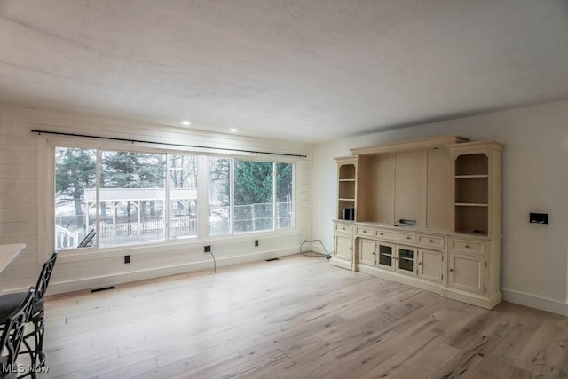 unfurnished living room featuring a wealth of natural light and light hardwood / wood-style flooring