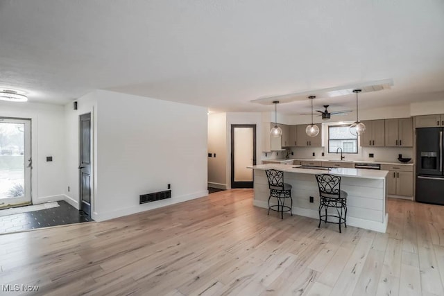 kitchen featuring gray cabinets, black appliances, a center island, and light wood-type flooring