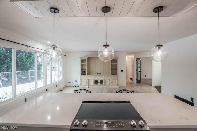 kitchen with stove, decorative light fixtures, light hardwood / wood-style floors, and a kitchen island