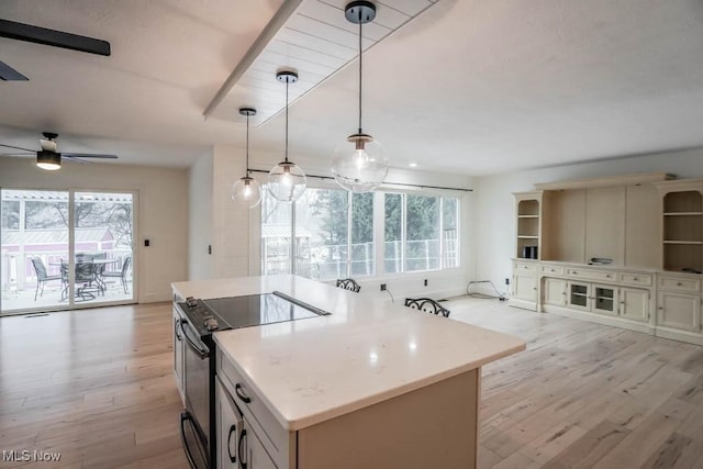 kitchen featuring range with electric cooktop, a healthy amount of sunlight, a center island, and hanging light fixtures