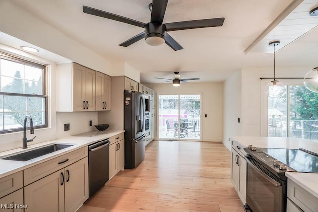 kitchen with sink, light hardwood / wood-style flooring, appliances with stainless steel finishes, gray cabinets, and pendant lighting