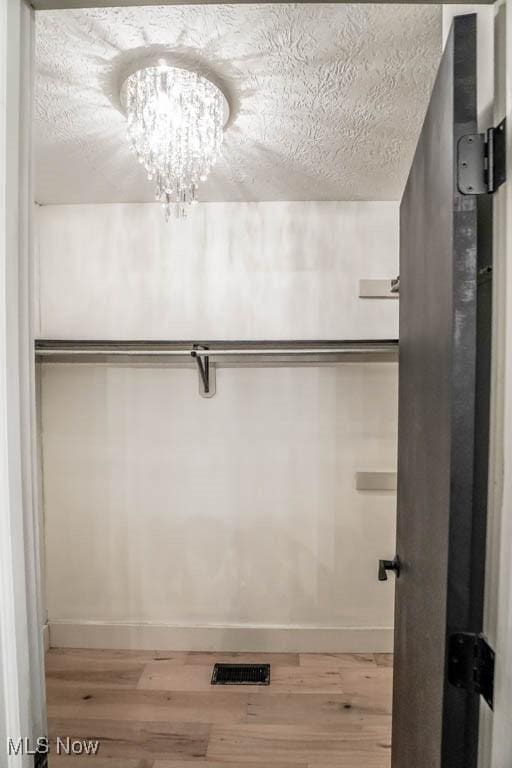 spacious closet featuring hardwood / wood-style flooring and a chandelier