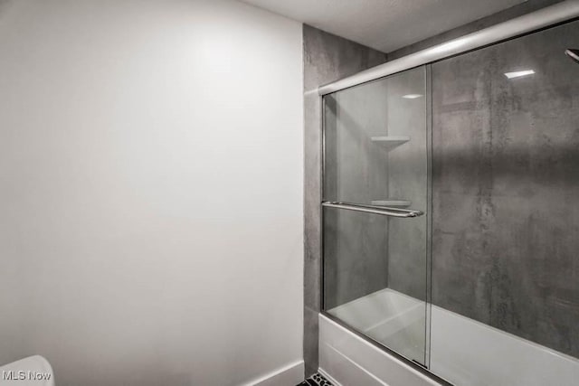 bathroom with bath / shower combo with glass door and toilet