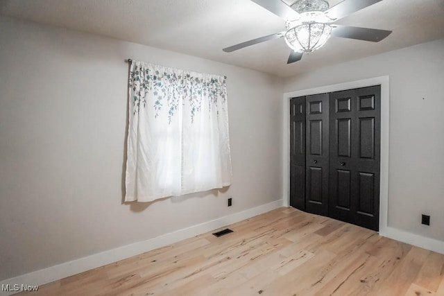 unfurnished bedroom featuring ceiling fan, a closet, and light hardwood / wood-style flooring