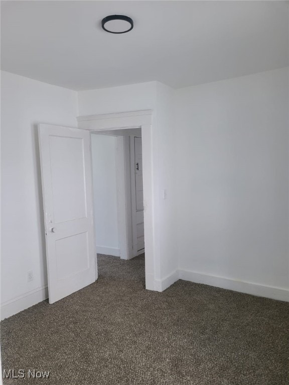 unfurnished room featuring dark carpet