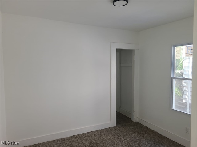 unfurnished bedroom featuring dark colored carpet and a closet