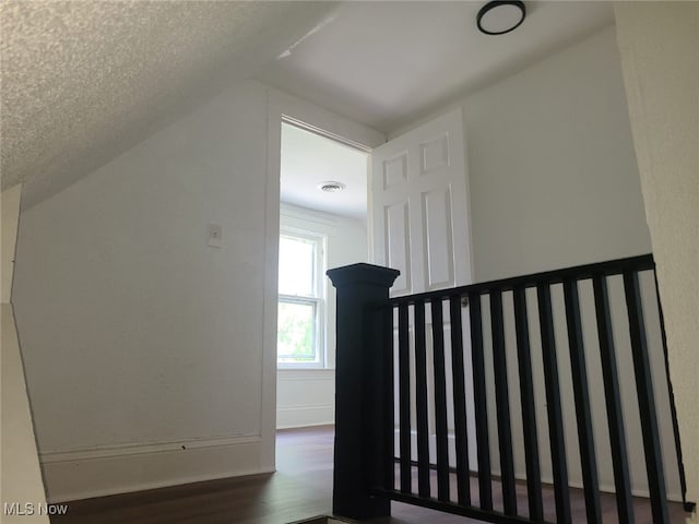 additional living space with dark hardwood / wood-style flooring, lofted ceiling, and a textured ceiling