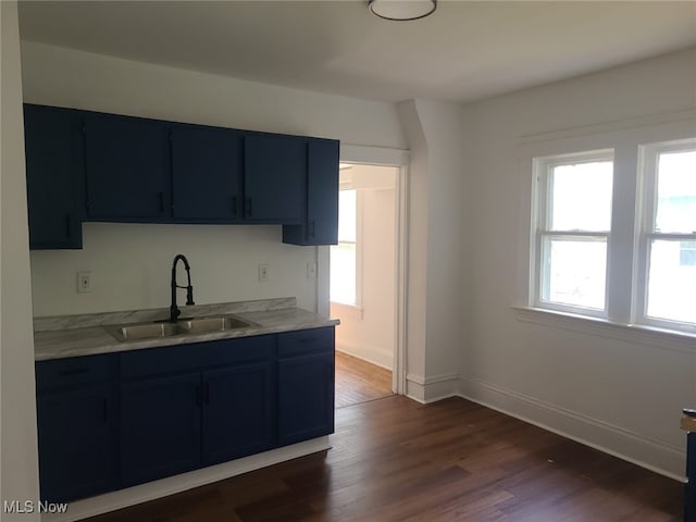 kitchen with light stone countertops, sink, dark hardwood / wood-style floors, and blue cabinets