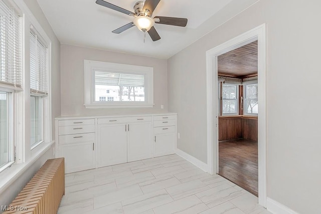 interior space featuring white cabinets, radiator heating unit, and ceiling fan