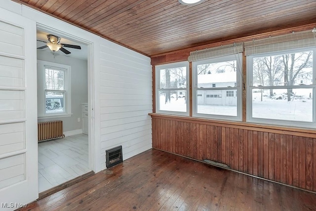 unfurnished sunroom with ceiling fan, radiator heating unit, and wood ceiling