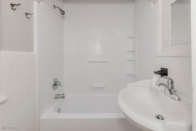 bathroom with shower / tub combination, sink, and tile walls