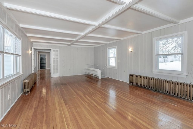 unfurnished living room with hardwood / wood-style floors, plenty of natural light, and radiator