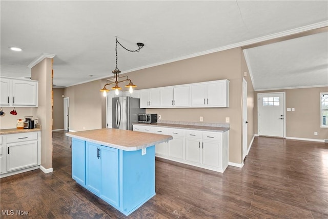 kitchen with pendant lighting, white cabinets, crown molding, appliances with stainless steel finishes, and a kitchen island