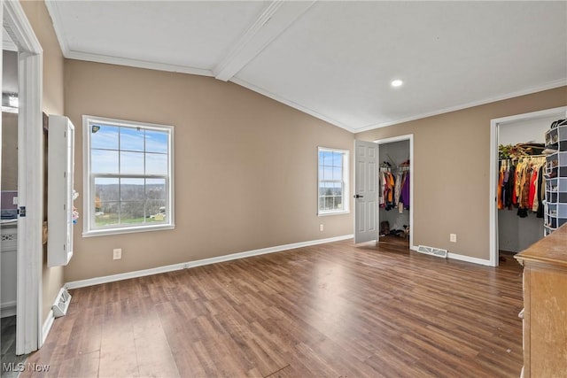 unfurnished bedroom with a walk in closet, ornamental molding, multiple windows, vaulted ceiling with beams, and dark hardwood / wood-style floors