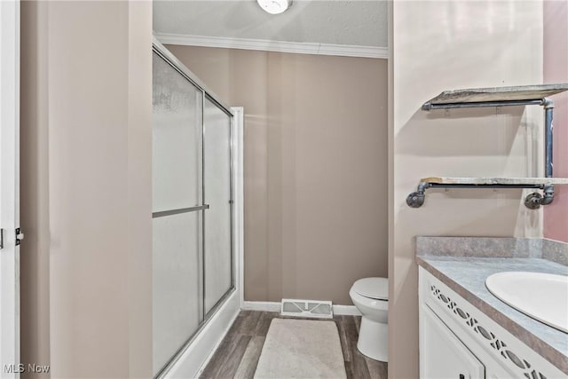 bathroom featuring crown molding, wood-type flooring, toilet, a shower with door, and vanity