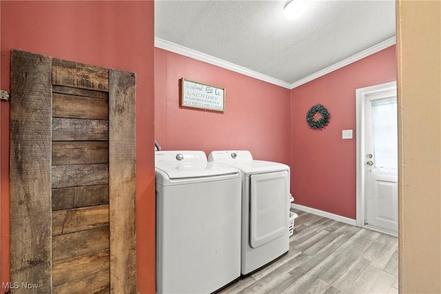 laundry room with a textured ceiling, separate washer and dryer, light hardwood / wood-style flooring, and crown molding