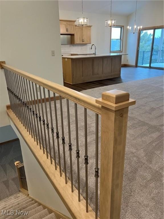 stairs with carpet floors, an inviting chandelier, and sink