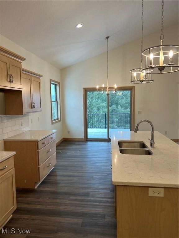 kitchen with a center island with sink, dark hardwood / wood-style floors, sink, and an inviting chandelier