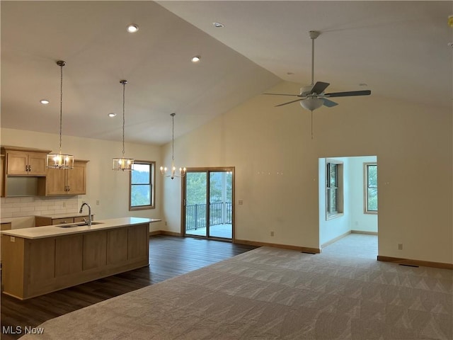 kitchen with sink, light brown cabinets, tasteful backsplash, high vaulted ceiling, and ceiling fan with notable chandelier