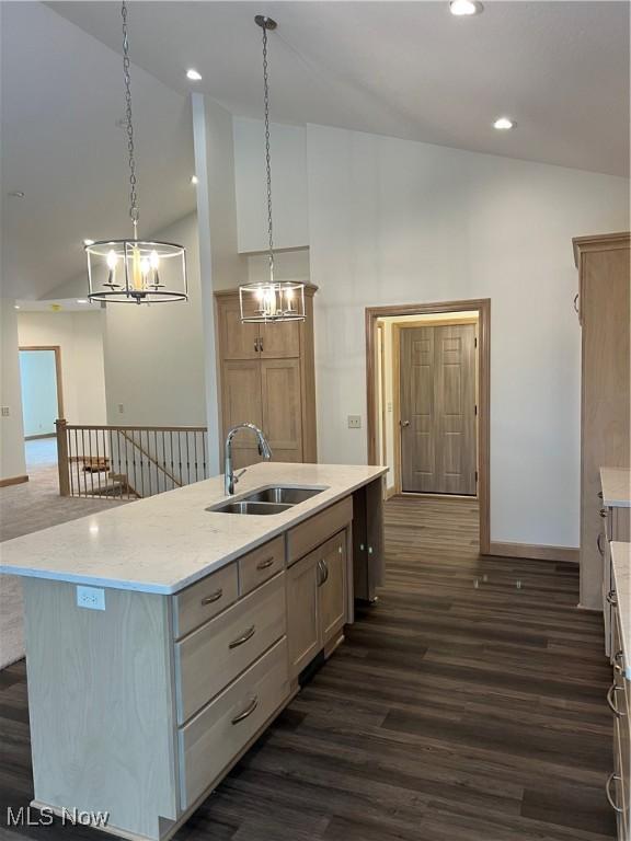 kitchen with light brown cabinetry, dark hardwood / wood-style flooring, sink, hanging light fixtures, and an island with sink