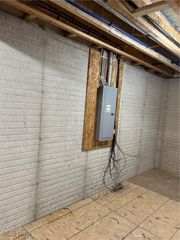 basement with electric panel and brick wall