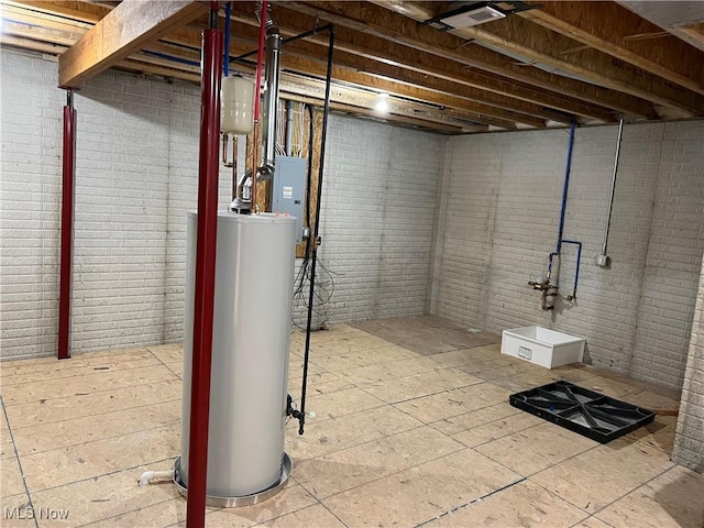 basement featuring brick wall, electric panel, and water heater