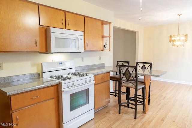 kitchen featuring a chandelier, a kitchen breakfast bar, white appliances, and light hardwood / wood-style floors