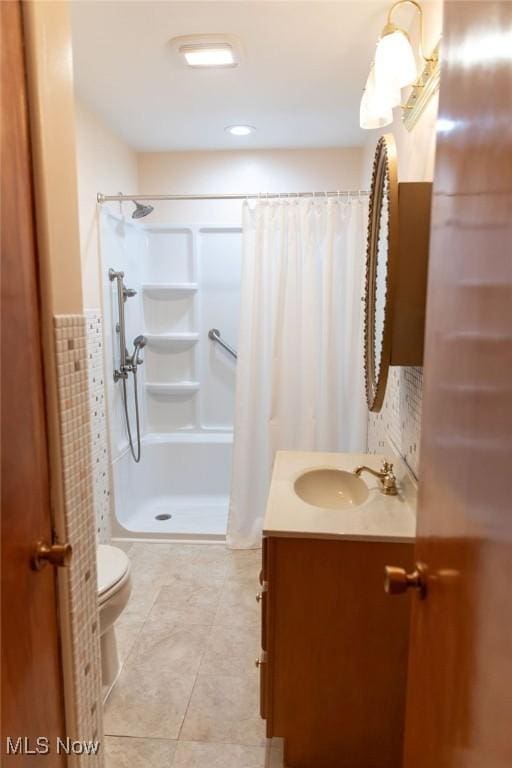 bathroom featuring curtained shower, tile patterned flooring, vanity, and toilet