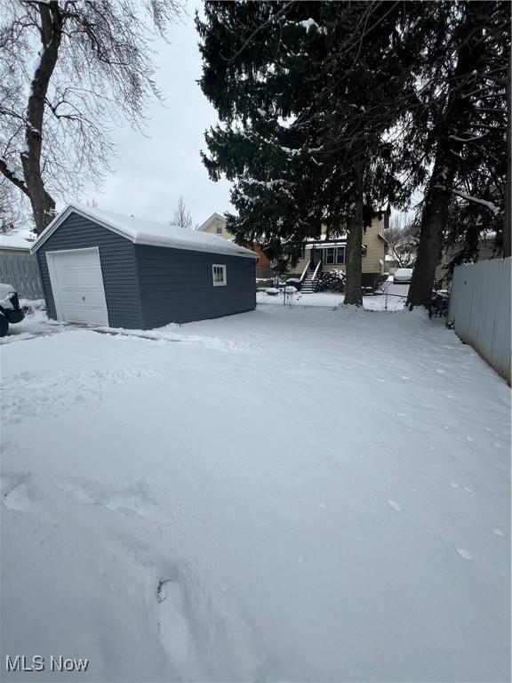 snowy yard with a garage and an outdoor structure