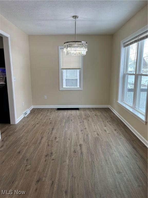 unfurnished dining area featuring hardwood / wood-style flooring and an inviting chandelier