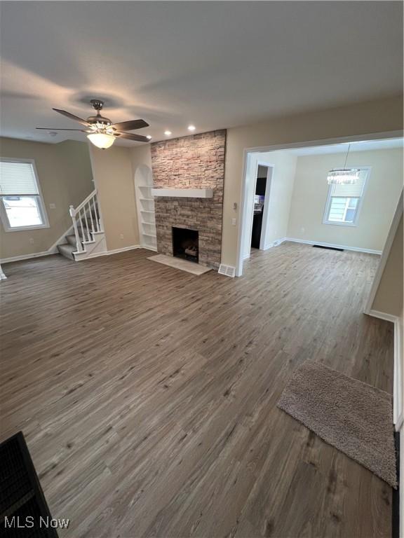 unfurnished living room featuring hardwood / wood-style flooring, built in shelves, ceiling fan, and a fireplace