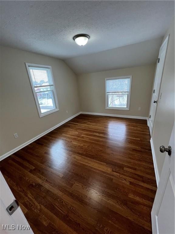 spare room with plenty of natural light, dark hardwood / wood-style floors, and vaulted ceiling