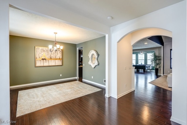 unfurnished room with dark hardwood / wood-style flooring and ceiling fan with notable chandelier