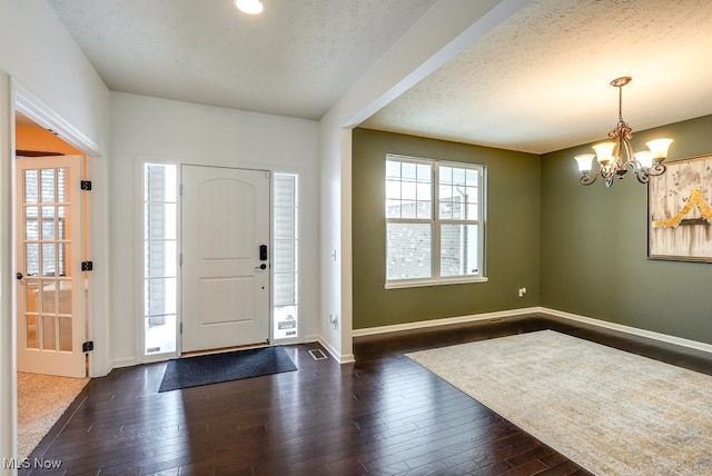 foyer with a textured ceiling, dark hardwood / wood-style floors, and an inviting chandelier