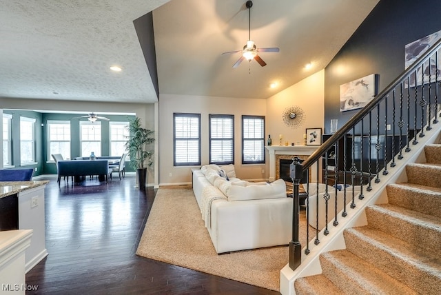 living room with dark hardwood / wood-style flooring, a textured ceiling, ceiling fan, and lofted ceiling