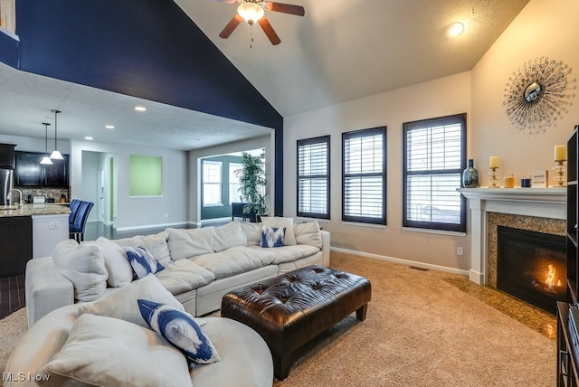 carpeted living room with ceiling fan and high vaulted ceiling