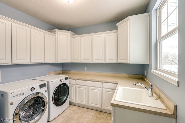 laundry room featuring cabinets, a textured ceiling, washer and dryer, and sink