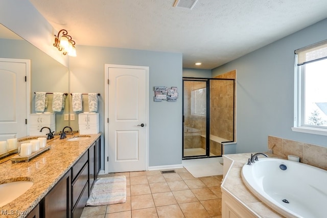 bathroom with plus walk in shower, a textured ceiling, vanity, and tile patterned floors