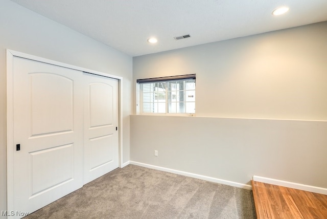 unfurnished bedroom with light colored carpet and a closet