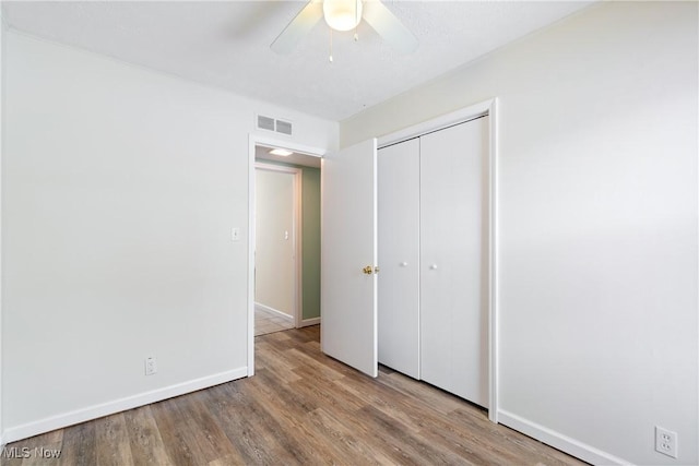 unfurnished bedroom featuring ceiling fan, a closet, and hardwood / wood-style floors