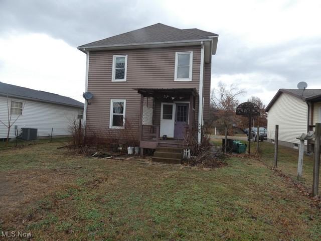 back of property featuring central AC unit and a lawn