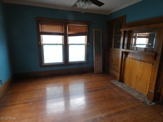 spare room featuring a healthy amount of sunlight, ceiling fan, crown molding, and hardwood / wood-style floors