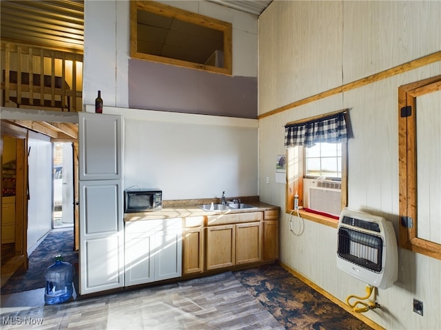 kitchen with a towering ceiling, heating unit, cooling unit, sink, and tile counters