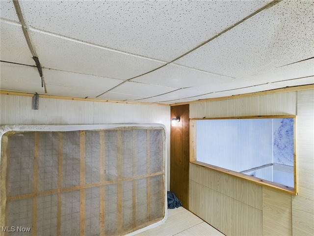 interior space with a drop ceiling and wooden walls