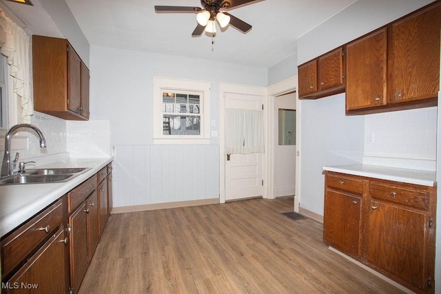 kitchen featuring decorative backsplash, light wood-type flooring, ceiling fan, and sink